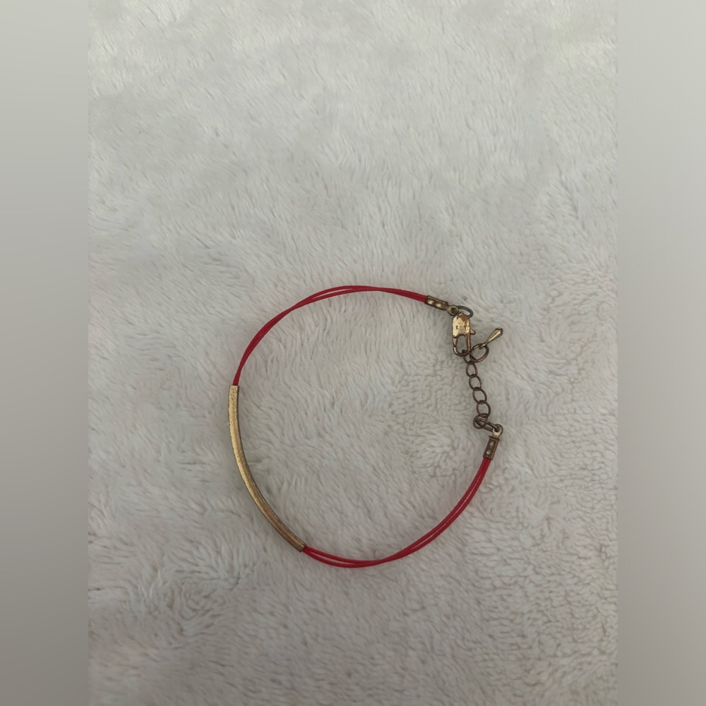 red/orange bracelet with gold/bronze accent bar.